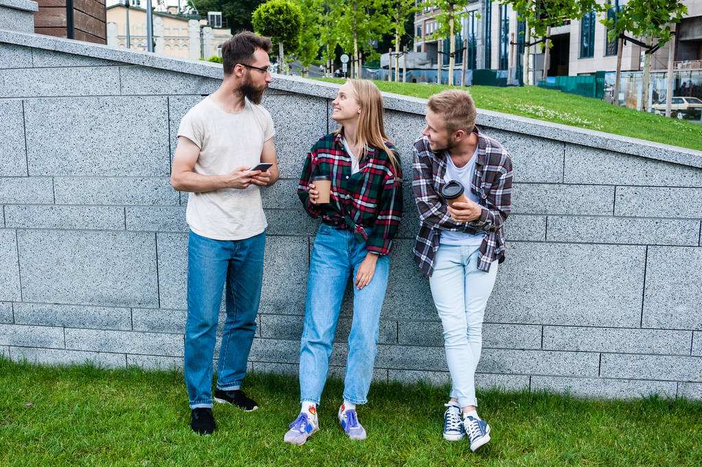 usmívající se mladí přátelé pomocí smartphone a pití kávy z papírových kelímků - Fotografie, Obrázek