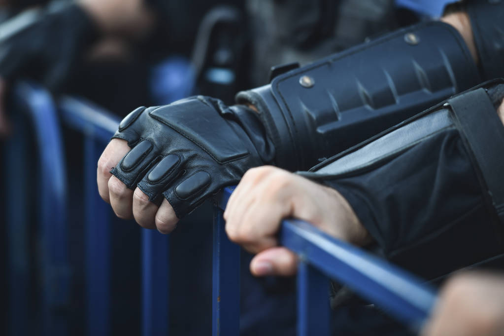 Oficial de policía manos en una valla de seguridad durante un motín
 - Foto, imagen