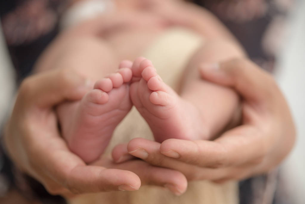 両親の手で生まれたばかりの赤ちゃんの足。幸せな家族の概念. - 写真・画像