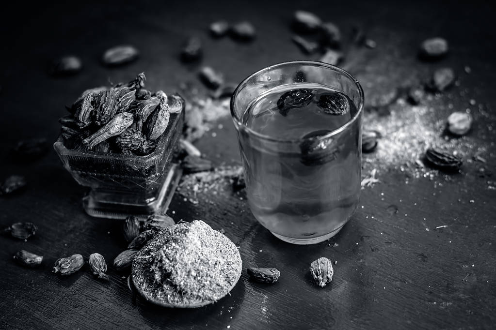 Close up of water of Black cardamom with its powder and raw whole black cardamom. - Photo, Image