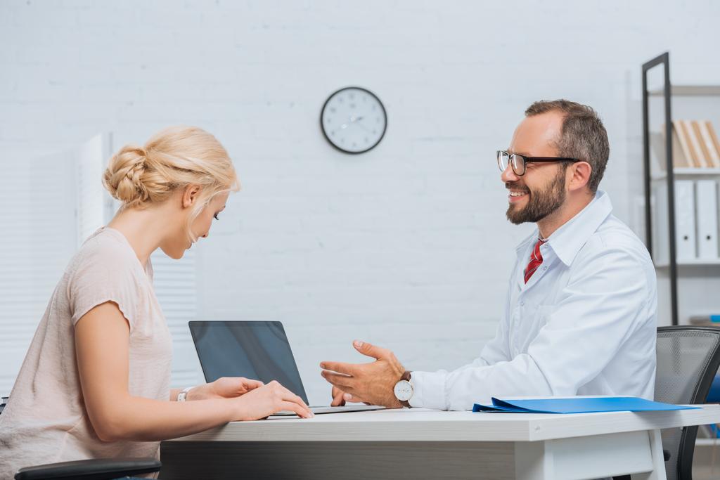 physiothérapeute en blouse blanche ayant une conversation avec une patiente sur le lieu de travail avec un ordinateur portable à l'hôpital
 - Photo, image
