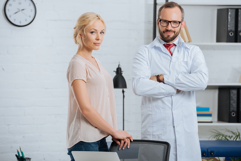 Porträt eines Arztes im weißen Kittel und einer Patientin, die in der Klinik in die Kamera blickt - Foto, Bild