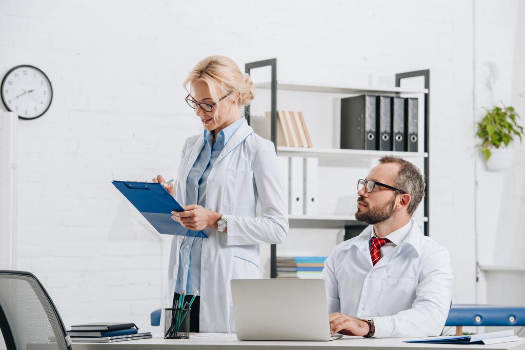 Porträt von Physiotherapeuten in weißen Kitteln und Brille am Arbeitsplatz in der Klinik  - Foto, Bild