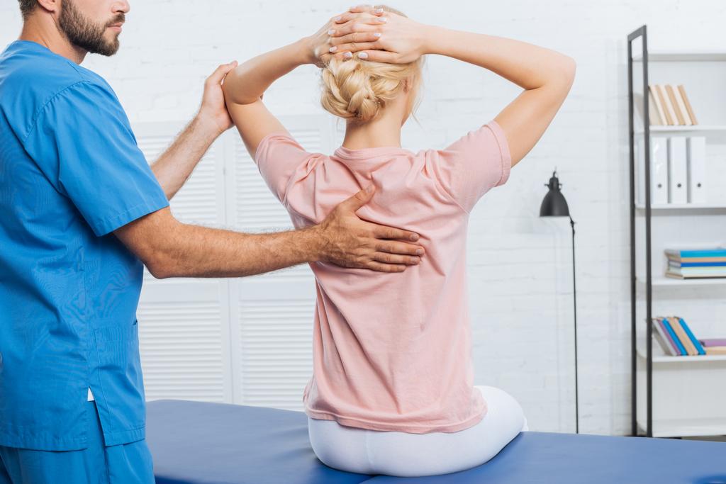 visão parcial do fisioterapeuta fazendo massagem à mulher na mesa de massagem no hospital
 - Foto, Imagem