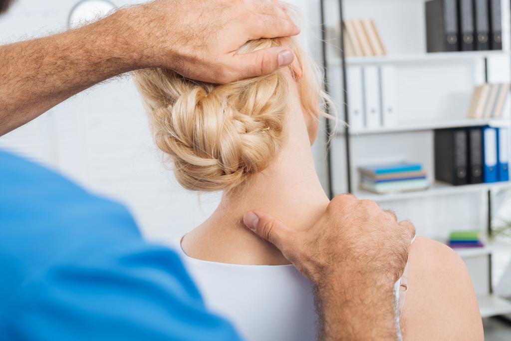 vue partielle du chiropraticien étirant le cou de la femme lors d'un rendez-vous à l'hôpital
 - Photo, image