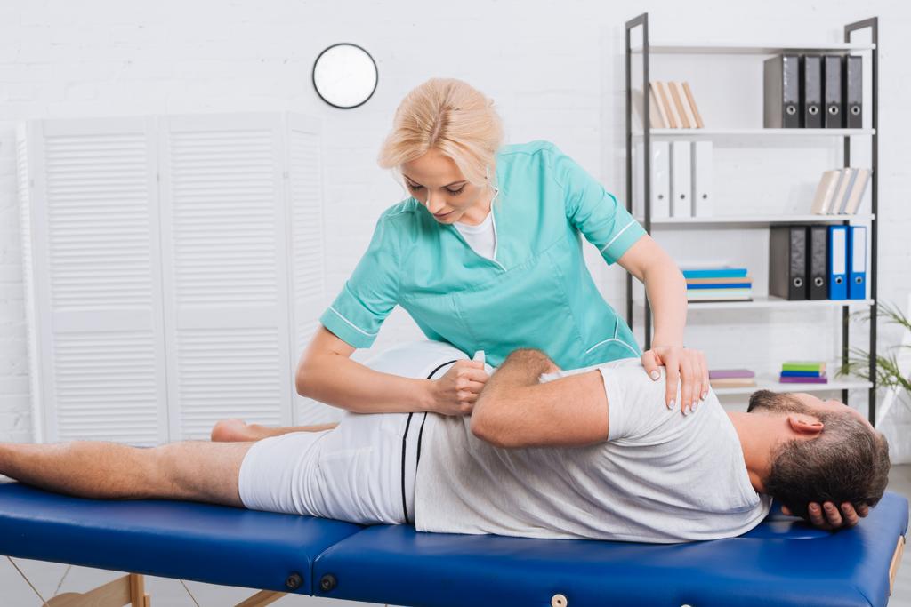 fisioterapeuta femenina haciendo masaje al paciente en mesa de masaje en el hospital
 - Foto, Imagen