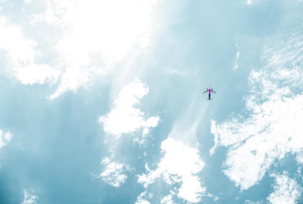 вид знизу літака, що летить у блакитному небі з білими хмарами
 - Фото, зображення