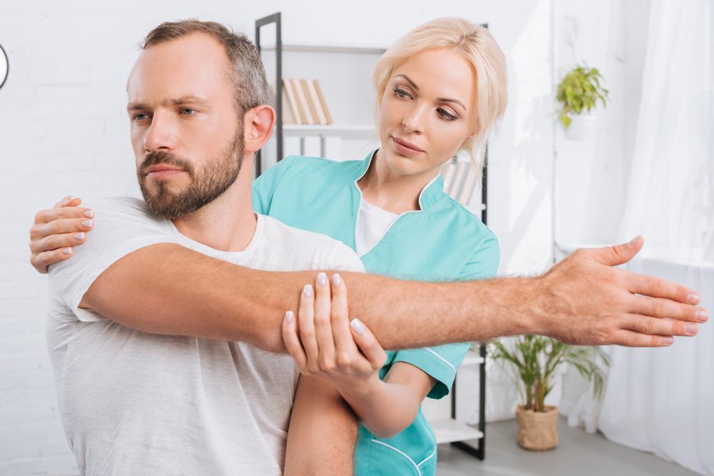 retrato de fisioterapeuta alongamento braço mans no hospital
 - Foto, Imagem