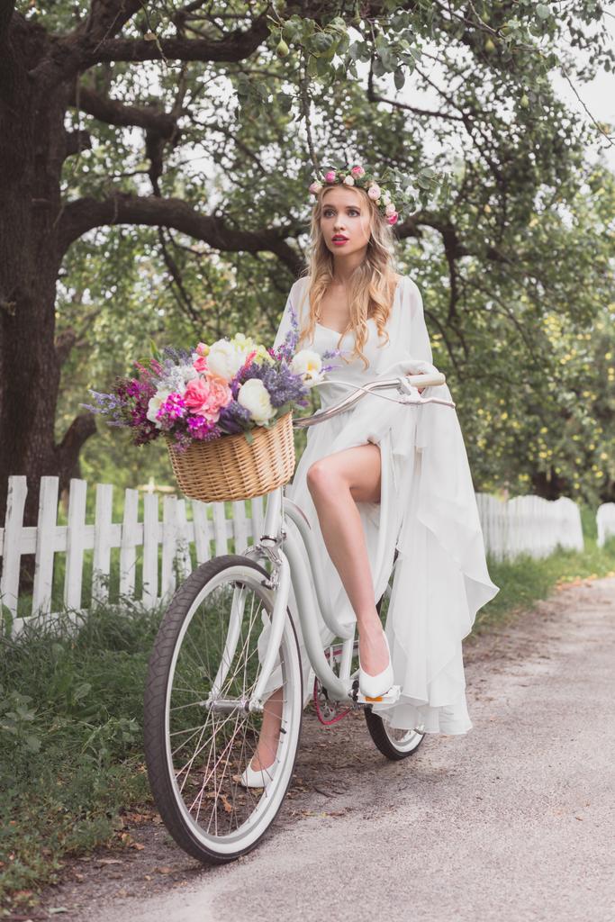 красива молода блондинка їзда на велосипеді з квітковим кошиком
  - Фото, зображення