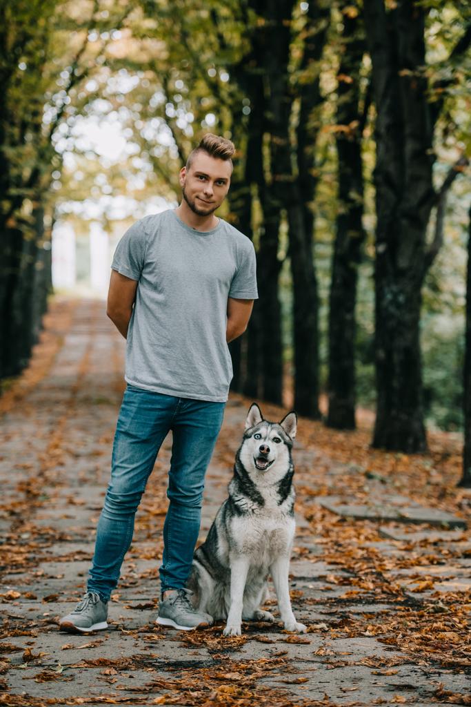 young man with siberian husky dog in autumn park - Photo, Image