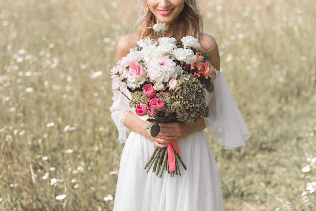 zbliżenie piękna panna młoda uśmiechający się trzymając bukiet kwiatów  - Zdjęcie, obraz