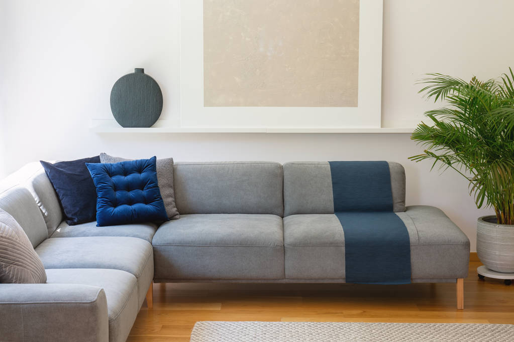 Синие подушки на сером угловом диване в интерьере гостиной с растительной и серебряной росписью. Настоящее фото
 - Фото, изображение