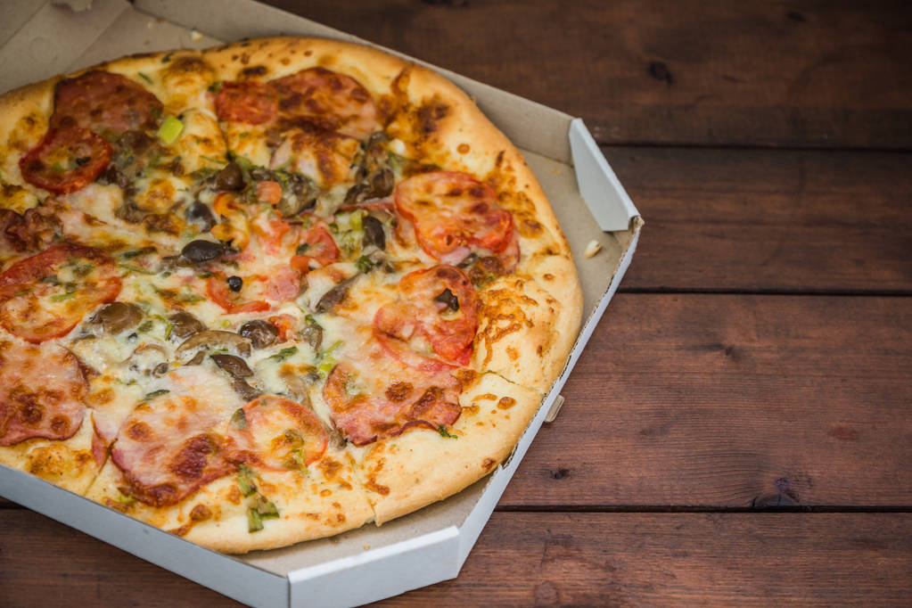 Піца на дерев'яні дошки в сільському стилі. Італійська піца у картонній коробці. Просту їжу на дерев'яними тлі. Смачні страви на обід - Фото, зображення