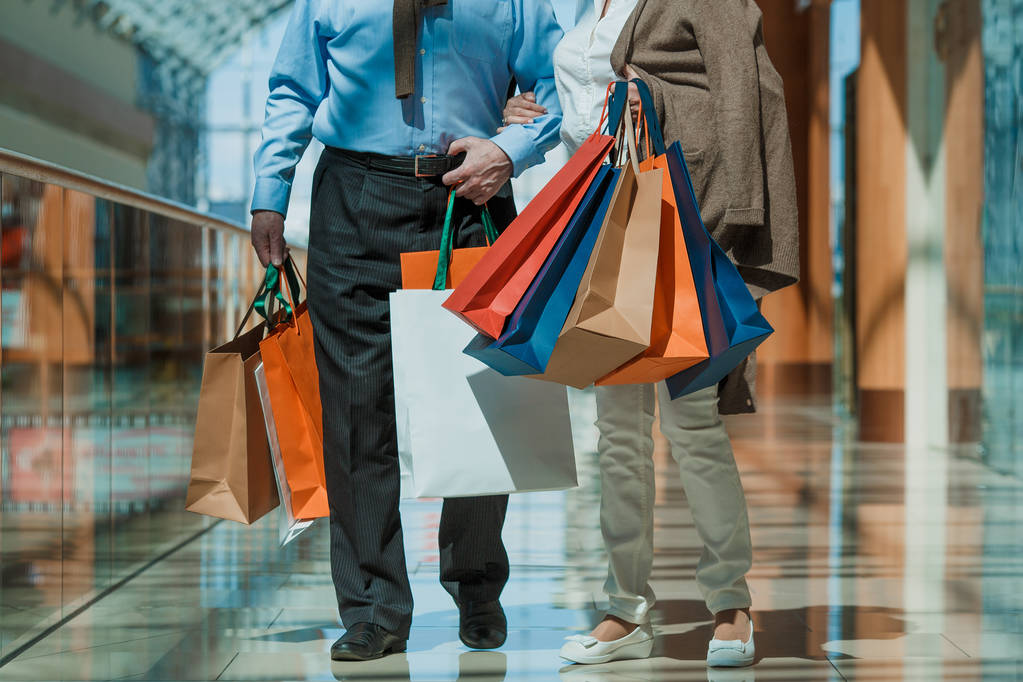 Взрослая пара с покупками в сумках в торговом центре
 - Фото, изображение