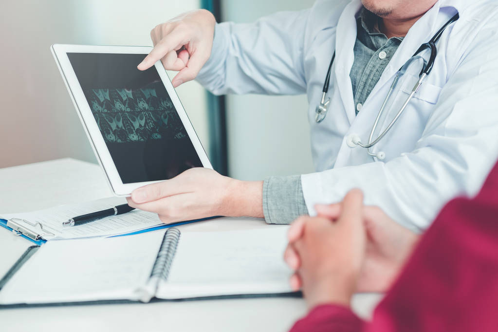 Ο γιατρός διαβούλευση με ασθενή παρουσίαση αποτελεσμάτων της ακτινογραφίας σε ψηφιακό tablet σχετικά με το πρόβλημα του ασθενούς - Φωτογραφία, εικόνα