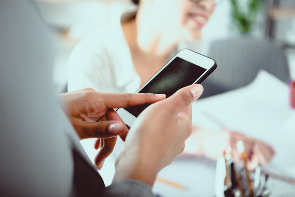 Обрезанный снимок бизнесвумен с помощью смартфона с чистым экраном
 - Фото, изображение