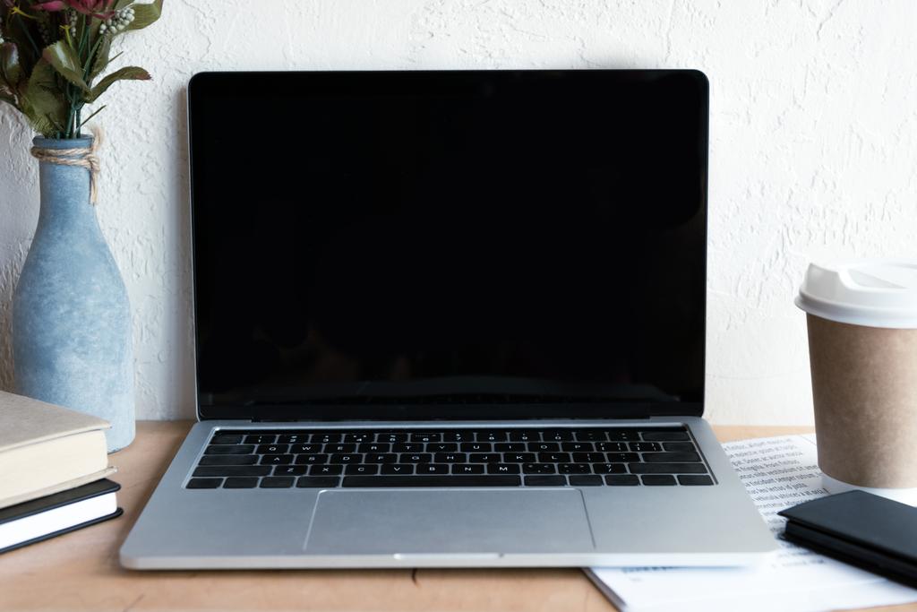 computer portatile con schermo bianco, giornale, smartphone, caffè da andare e libri sul tavolo
 - Foto, immagini
