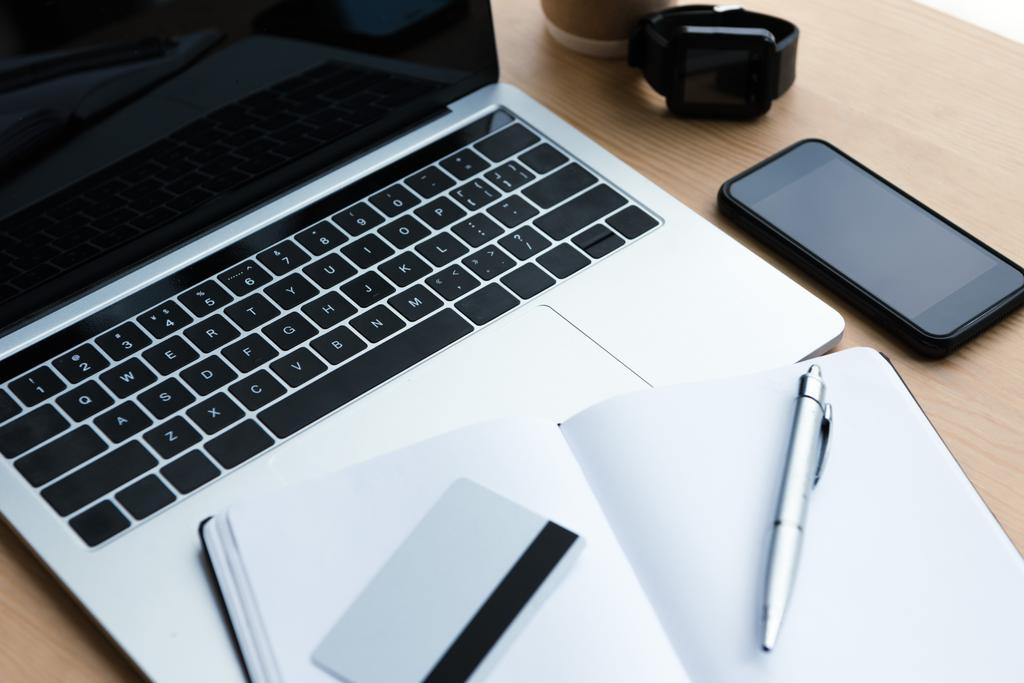 laptop, smartphone, smartwatch a prázdný zápisník s perem a kreditní kartou na dřevěný stůl - Fotografie, Obrázek