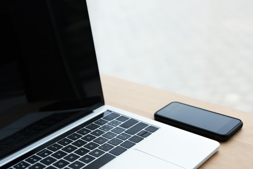 laptop i smartphone z czarne ekrany na drewnianym stole  - Zdjęcie, obraz