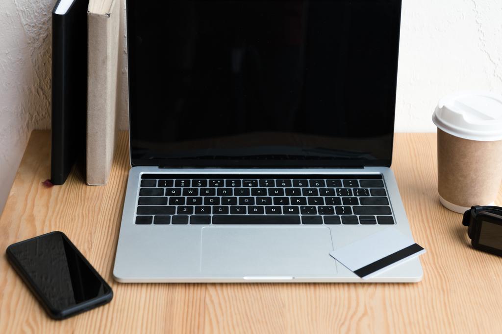 alto angolo di visualizzazione del computer portatile con schermo bianco, carta di credito e smartphone su tavolo in legno
 - Foto, immagini
