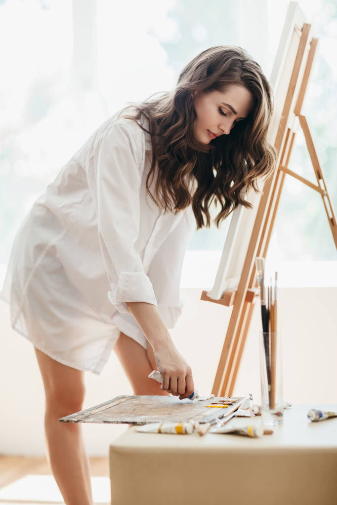 Nainen taiteilija sekoittamalla harjalla väri öljymaalaus paletti. Maalausprosessi taidehuoneessa
 - Valokuva, kuva