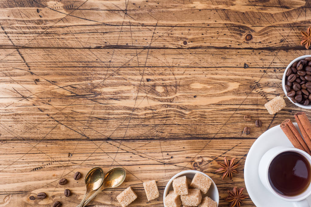 Kopje koffie, bruine suiker en kaneel met anijs op een houten achtergrond. Kopiëren van ruimte. - Foto, afbeelding