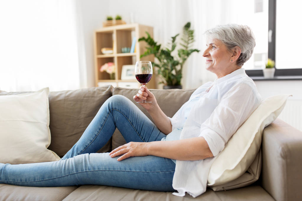 Senior kobieta z kieliszek czerwonego wina w domu - Zdjęcie, obraz