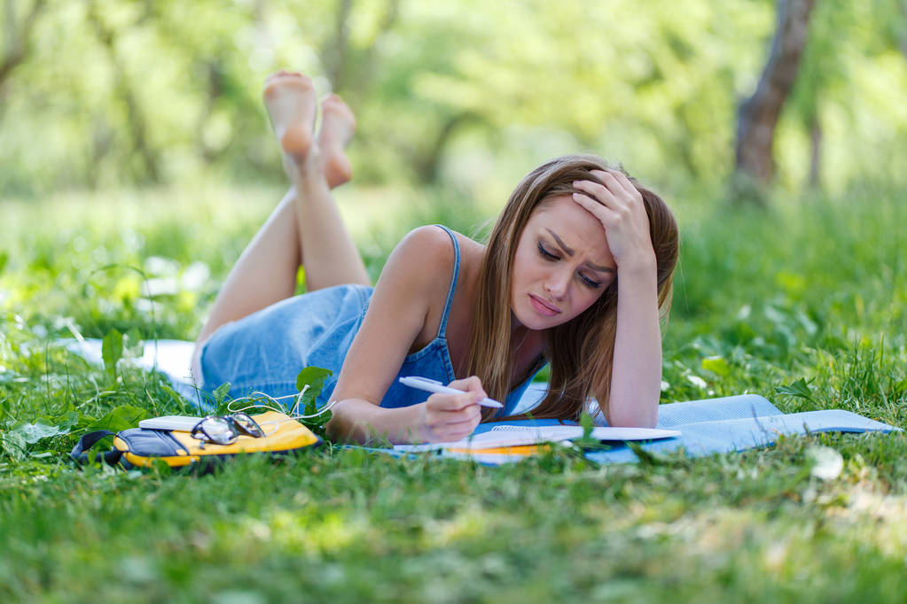 Beautiful young woman writing in her notebook, in the park - Photo, Image