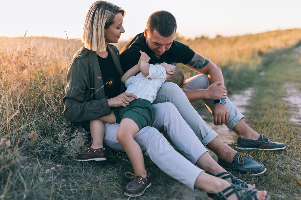 beautiful happy young family with one child spending time together outdoors at sunset - Photo, Image