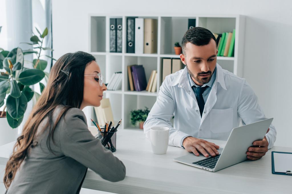 pacjenta i lekarza, patrząc na laptopie w klinice  - Zdjęcie, obraz