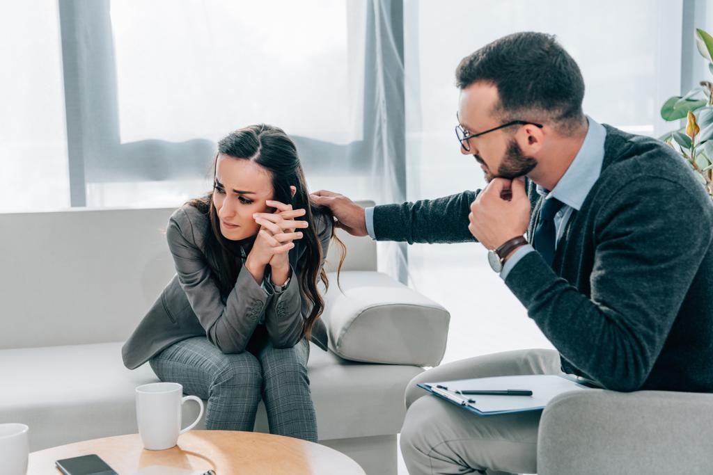 Ψυχολόγος αγγίζει στον ώμο του κλάμα ασθενή στο γραφείο ιατρών  - Φωτογραφία, εικόνα
