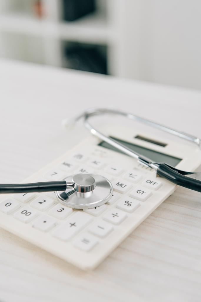 stethoscope lying on white calculator, health insurance concept - Photo, Image