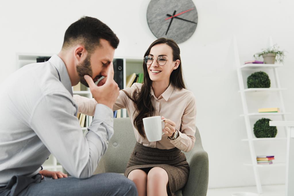 pszichológus ad csésze teát ideges beteg irodában mosolyogva - Fotó, kép