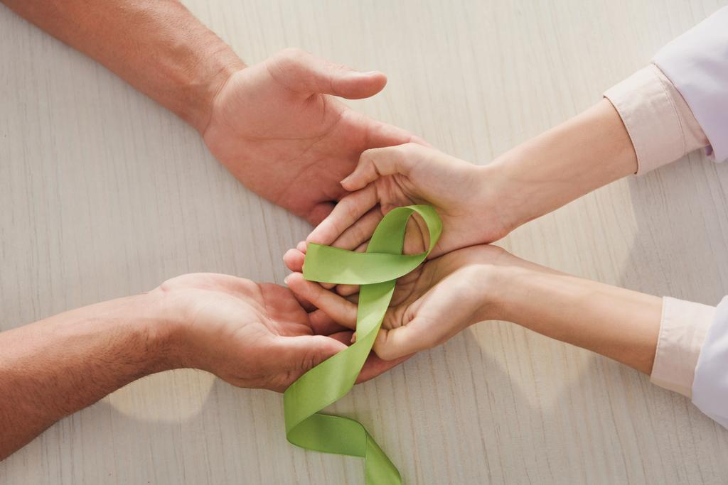 частковий вид чоловічих і жіночих рук з зеленою стрічкою день психічного здоров'я
 - Фото, зображення
