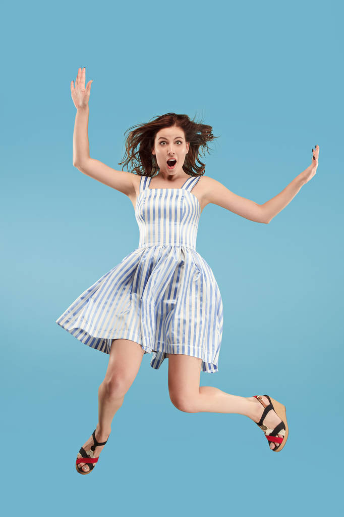 Свобода в русі. Гарненька молода жінка стрибає на синьому фоні
 - Фото, зображення