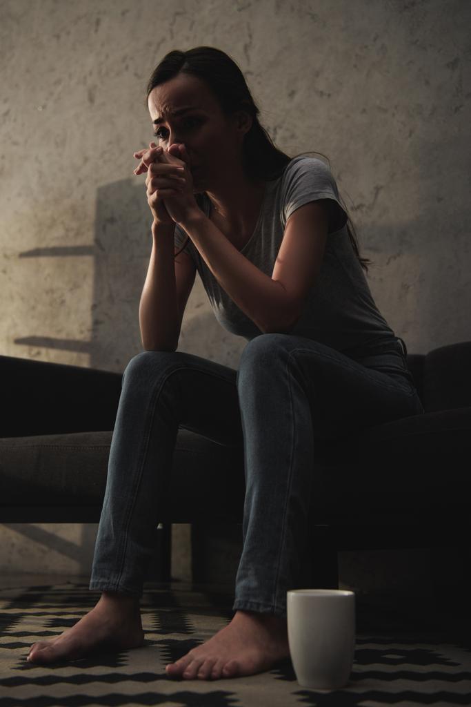 bottom view of crying woman sitting on sofa with coffee cup on floor - Photo, Image