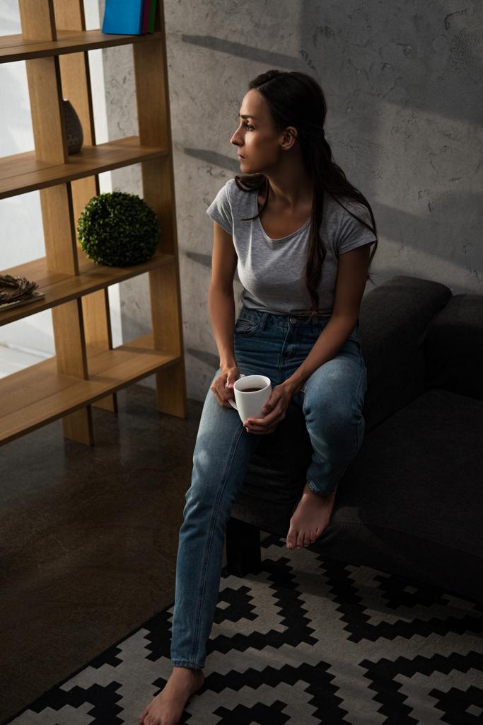 mujer molesta con taza de café sentado en el sofá
 - Foto, imagen