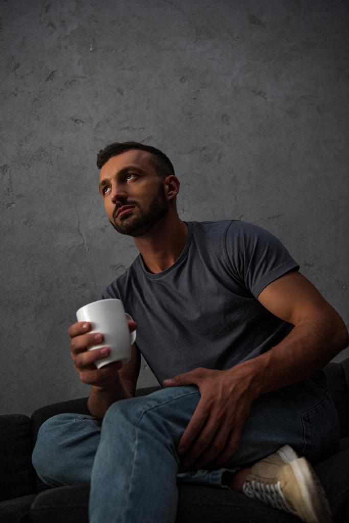 pohled zdola osamělý muž, který držel šálek kávy doma - Fotografie, Obrázek