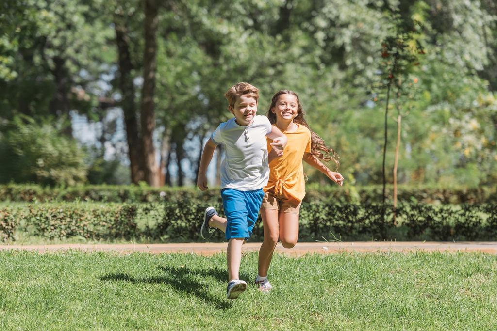 公園の芝生の上を実行している美しい幸せな子供たち - 写真・画像