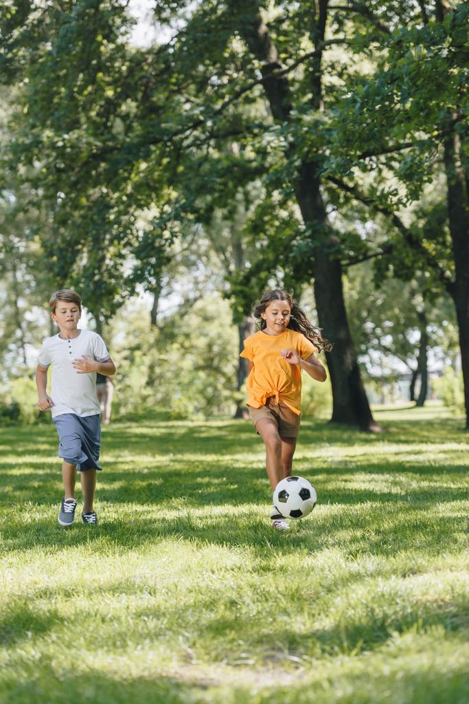 niedliche glückliche Kinder spielen mit Fußball im Park  - Foto, Bild