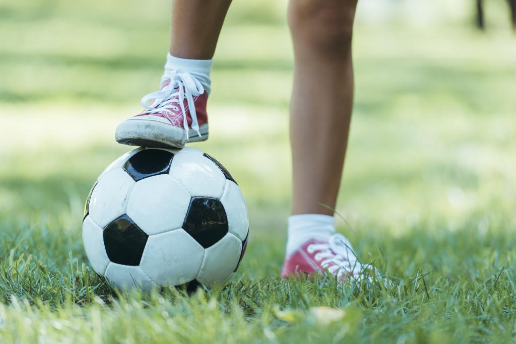 ritagliato colpo di bambino in piedi con pallone da calcio su erba
 - Foto, immagini