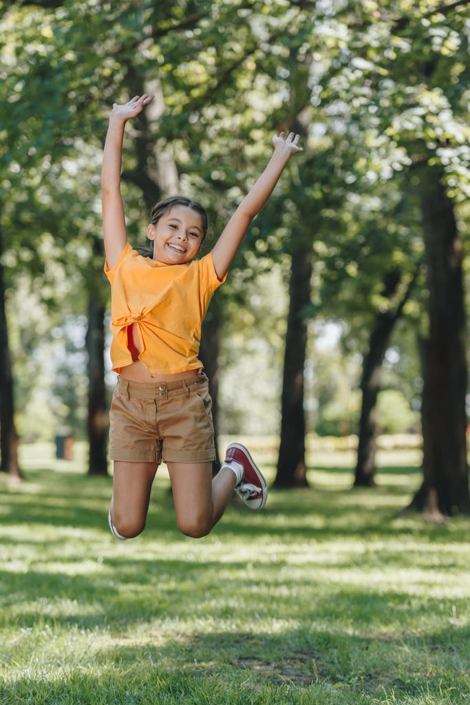 adorable enfant heureux sautant et souriant à la caméra dans le parc
  - Photo, image