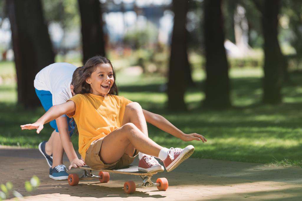adorable happy kids having fun with longboard in park  - Photo, Image