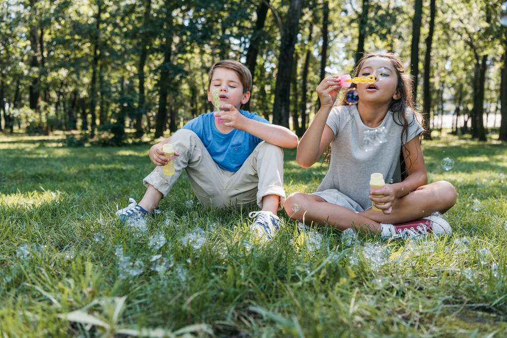 rozkošné děti foukání mýdlové bubliny v parku - Fotografie, Obrázek
