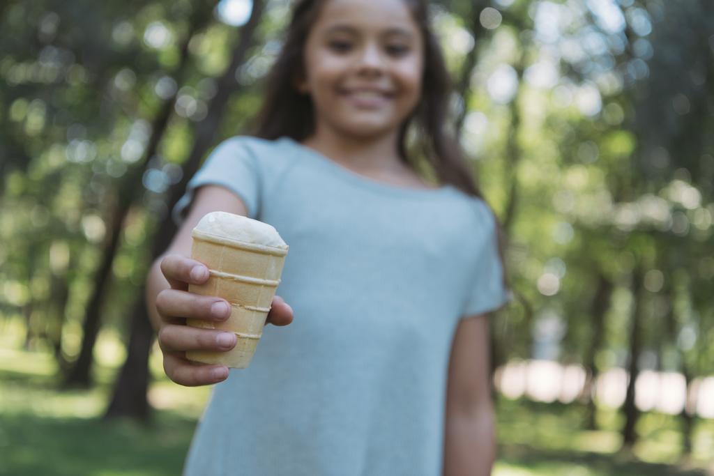 избирательный фокус очаровательного ребенка, держащего мороженое и улыбающегося на камеру в парке
 - Фото, изображение