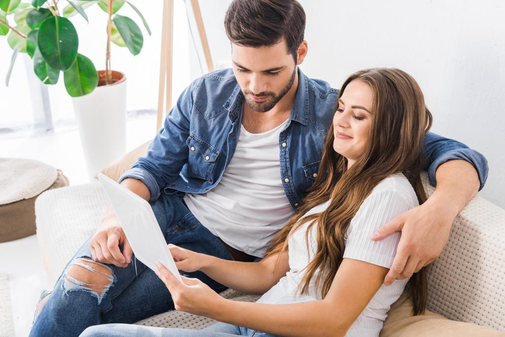 Nuori pari istuu sohvalla digitaalinen tabletti kotona
  - Valokuva, kuva