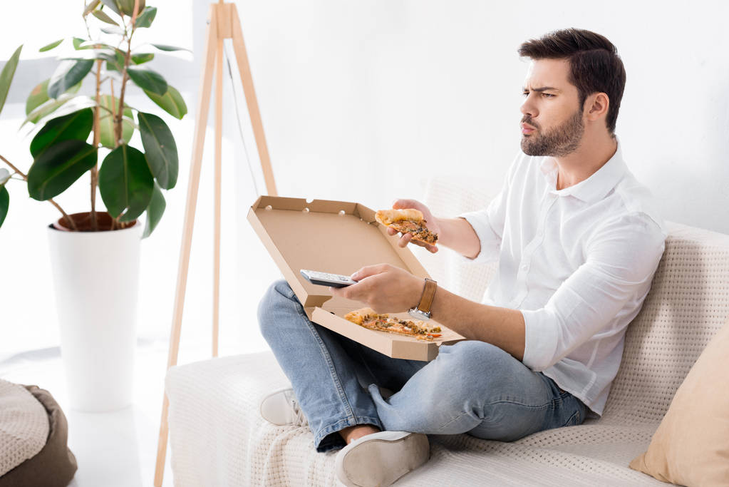 hombre comiendo pizza mientras viendo tv solo en casa
 - Foto, Imagen