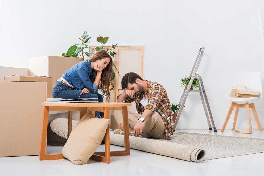 Müdes junges Paar im neuen Haus mit Pappkartons, Umzugskonzept - Foto, Bild