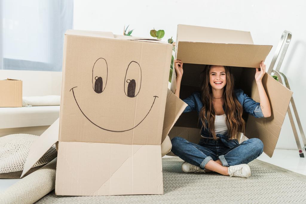 happy woman with cardboard boxes sitting on floor at new home - Photo, Image