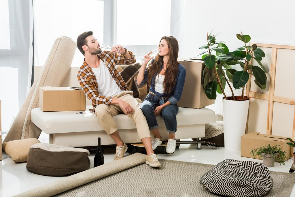 couple in love drinking champagne at new house with cardboard boxes, moving home concept - Photo, Image
